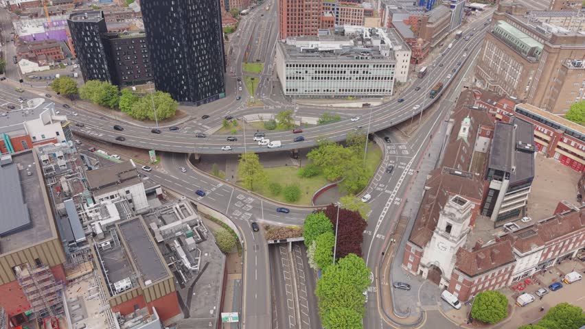 Cinematic drone flyover capturing busy roads, flowing traffic and striking modern and historic architecture in Birmingham city centre, England.