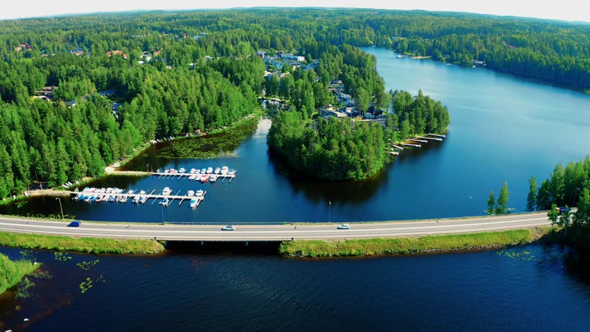 Stunning Aerial View of Serene Lake Surrounded by Lush Forest and Scenic Highway Traffic in Finland