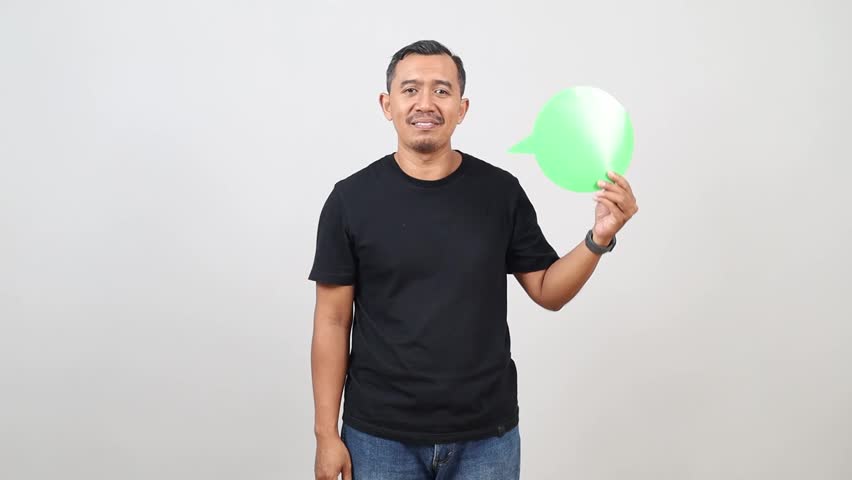 Asian man holding speech bubble over isolated white background with a happy face standing and smiling with a confident smile