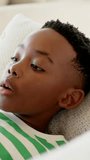 Vertical video: Tracking boy in striped shirt lying on sofa with white pillow, tracking left motion. Portrait, child, closeup, gaze, focus, calm, vertical video - Powered by Shutterstock - Get 15% off with code: PIKWIZARD15