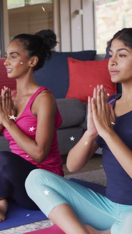 Vertical video: After stars appear, mom and daughter breathing, opening palms on yoga mats for calm. Duo, meditation, patio, sunroom, cushions, greenery, vertical video