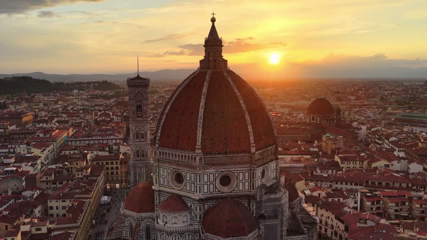 Aerial sunset orbiting shot of Florence Duomo, famous Renaissance cathedral in Florence, Italy,  setting sun behind the cathedral 