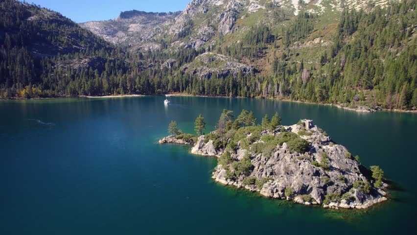 Drone footage pulling back from Fannette Island revealing the full Emerald Bay landscape and surrounding mountains.
