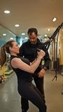 Male personal trainer instructing a determined woman during a suspension training workout. Professional fitness coach guiding his client's form - Powered by Shutterstock - Get 15% off with code: PIKWIZARD15