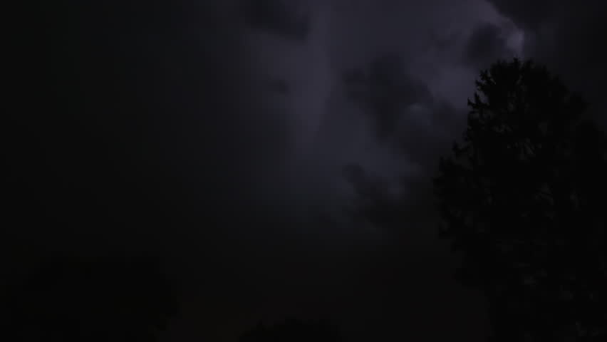 Lightning strikes on a dark night sky over a city landscape, captured in slow motion.