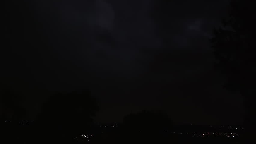 Lightning strikes on a dark night sky over a city landscape, captured in slow motion.