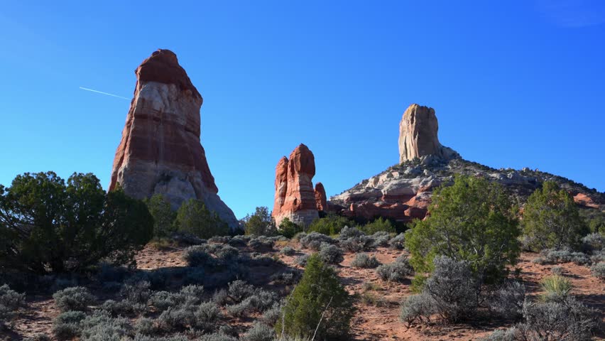 A geological formation appears to be a large sandstone butte is likely located near Page, Arizona, on the Navajo Nation land. It is a prominent sandstone summit, often referred to as a "square rock" or "square butte". The structure is surrounded by desert scrub and sagebrush, typical of the Colorado Plateau region.