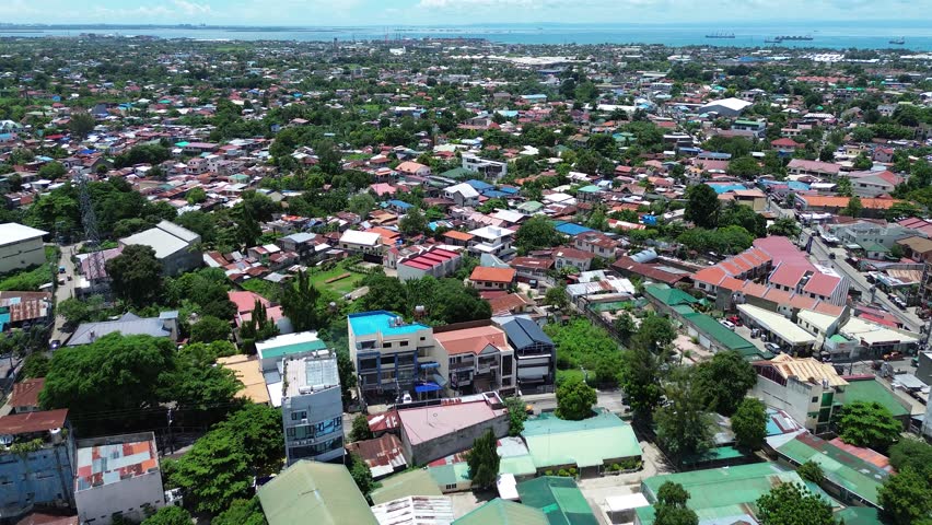 Drone flight over urban landscape in Talisay Philippines showing compact housing, roads and city development.