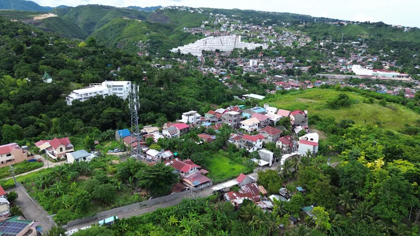 Drone flight over urban landscape in Talisay Philippines showing compact housing, roads and city development.
