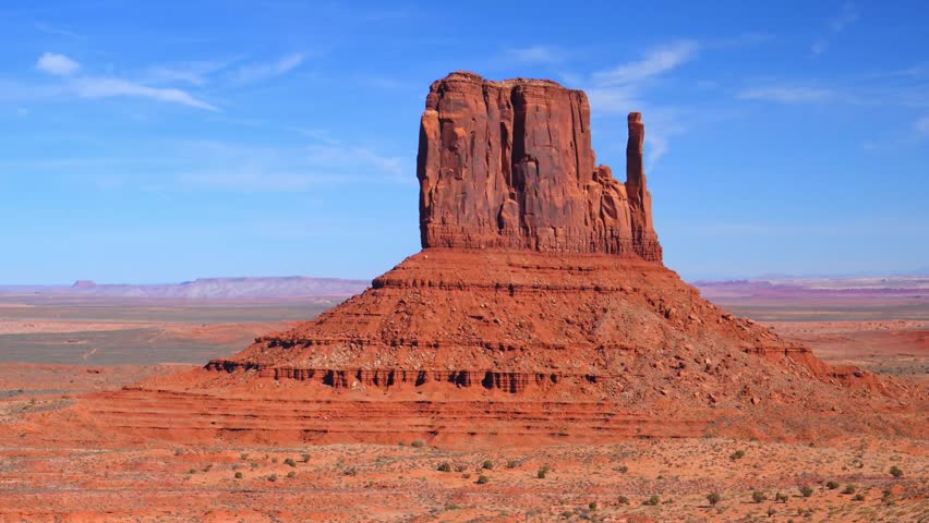 West Mitten Butte in Monument Valley, a famous landmark located on the border of Arizona and Utah. It is part of the Monument Valley Navajo Tribal Park. The buttes are made of orange-red sandstone and were formed by wind and water erosion. The area is significant to the Navajo Nation, and tours are typically run by Navajo guides. Monument Valley has been featured in numerous Hollywood films, including Forrest Gump and Back to the Future III.