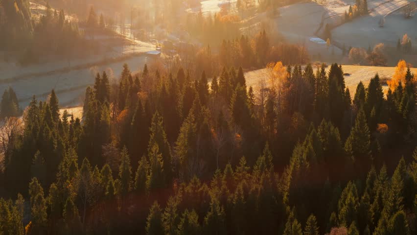 Dawn in the mountains in autumn. Sun rays break through the morning fog.