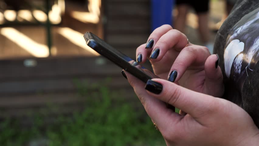 hand of a woman using a mobile phone reads a phone message and browses the news on the internet on a smartphone