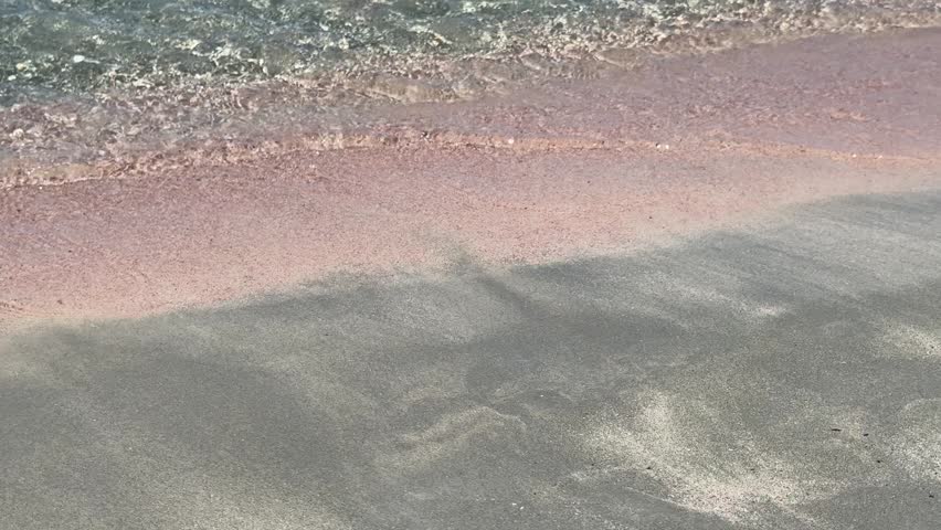 Pink sand and clear turquoise water at Elafonisi Beach on Crete, Greece. Peaceful seaside landscape with gentle waves, summer travel atmosphere, and natural Mediterranean beauty. Horizontal video.