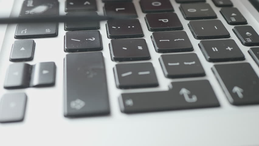 Close-up of person removing a laptop keyboard key for cleaning and repair.