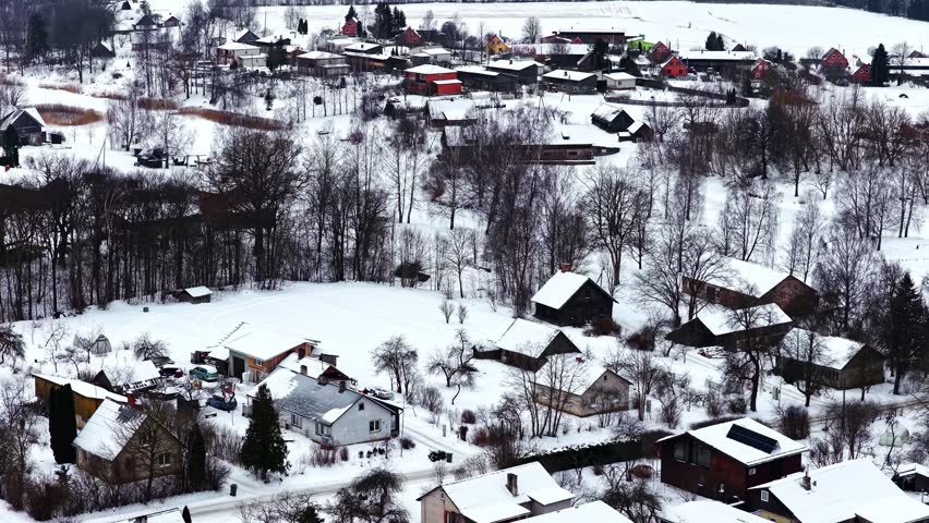 Village houses and trees covered by white snow, representing winter in a small community, wide aerial view