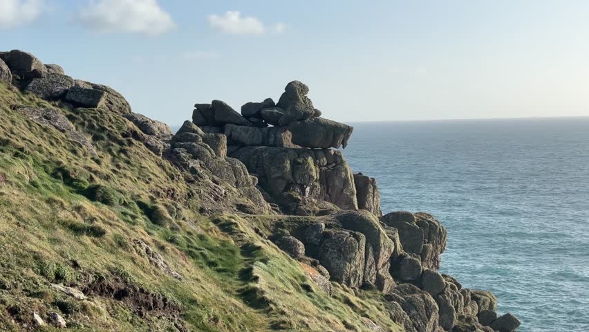 Rugged granite cliffs at Lands End in Cornwall overlooking vast Atlantic Ocean on clear day with textured rock formations and coastal landscape creating dramatic natural scene