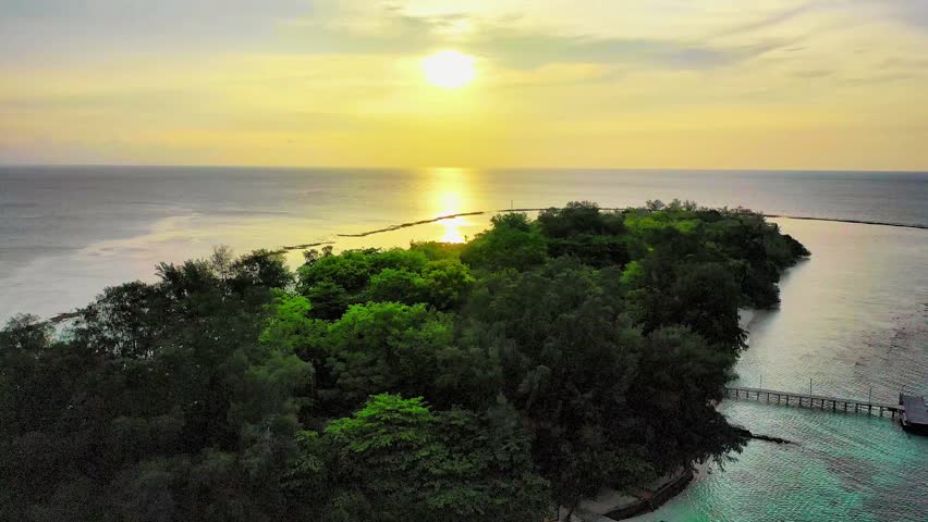 Beautiful nature sunset over a coastal landscape, featuring glowing sun near the horizon, calm sky gradients, and serene beach scenery capturing the peaceful transition from day to dusk.