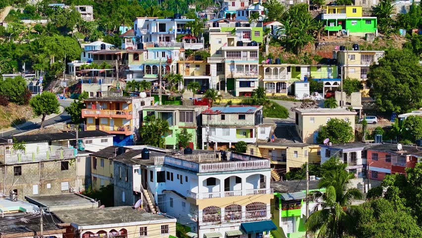 A small town with a mountain range and a nature park in the background. Mountains on the horizon with vegetation and parks around the buildings. A small mountain province on a sunny summer day.
