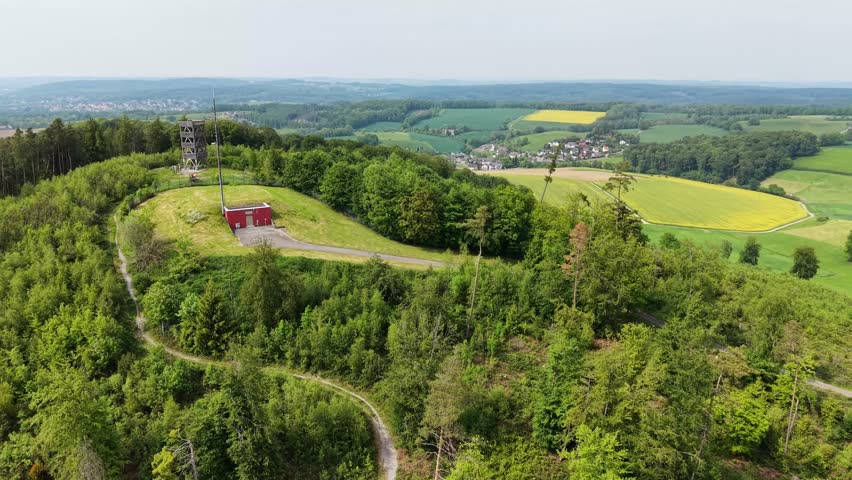 Scenic aerial view circling a telecommunication tower and a red hut on a lush green hill