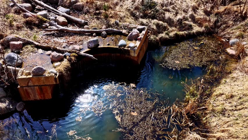 Rock formation with small pool of clear water in rugged natural terrain setting