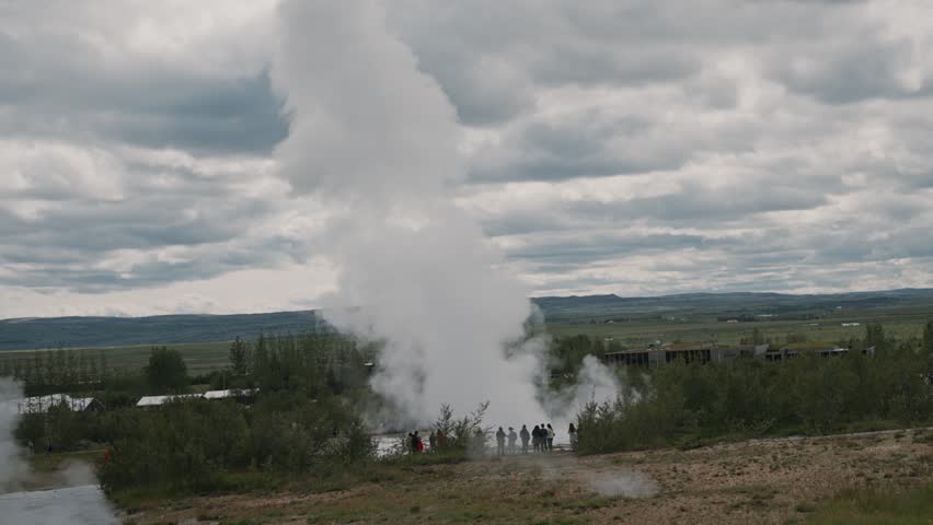 Strokkur geyser erupting with steam clouds and tourists in Haukadalur geothermal area Iceland