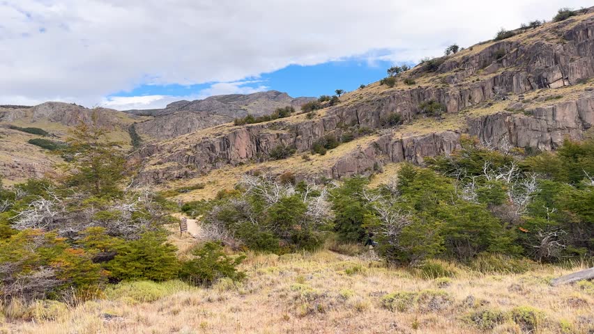 Hikers walking on a scenic trail in the mountains of Patagonia, Argentina. Beautiful rocky hills and wild nature under a blue sky during a trekking adventure in Los Glaciares