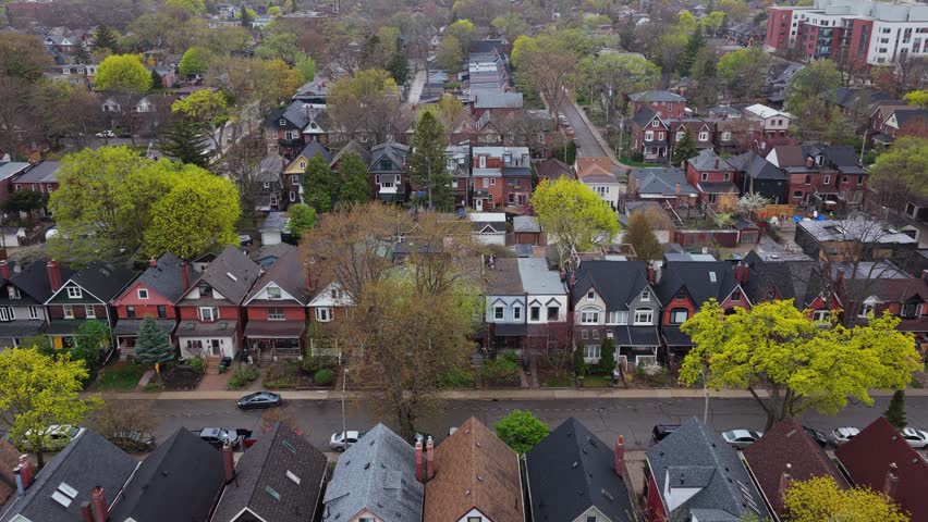 Residential neighborhood with typical victorian style houses, lush green trees and streets with cars during quiet day in North America