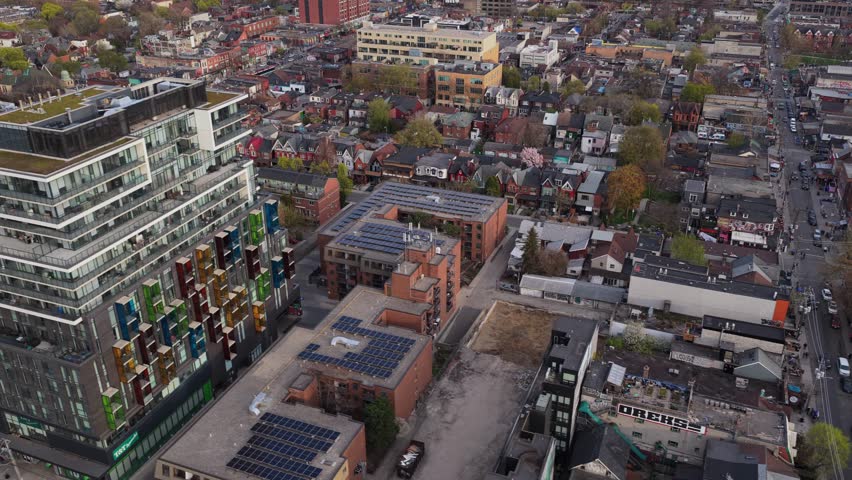 Flying over modern buildings and residential district, tilting up to reveal Toronto downtown skyline with CN Tower and financial district during daytime