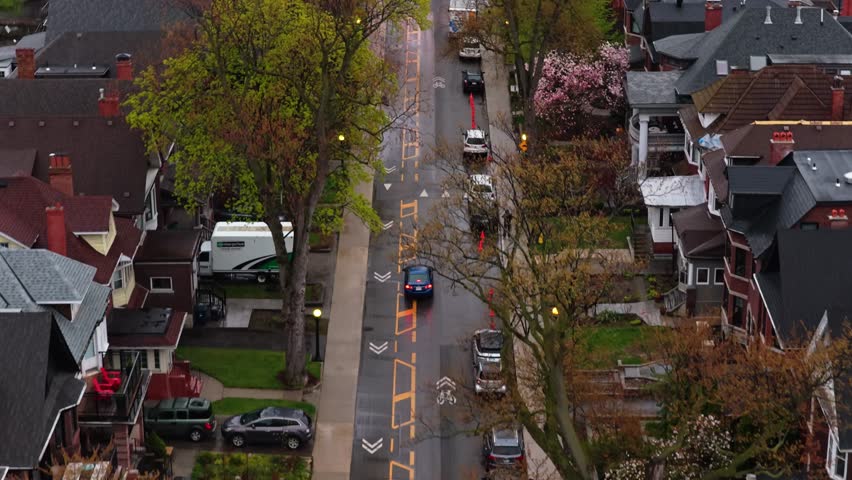 Urban landscape showcasing bicycle lanes and street markings with vehicles driving through a residential neighborhood on an overcast day in Toronto, Canada