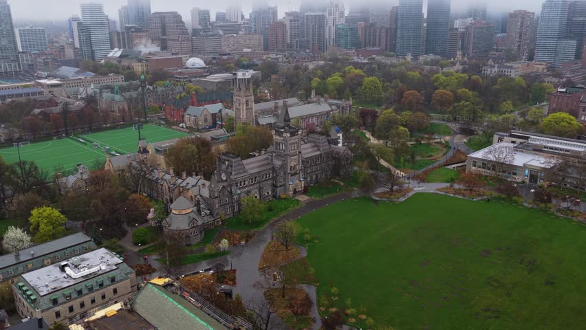 University of Toronto Trinity College and city skyline on a rainy day in downtown Toronto, Ontario, showcasing gothic revival architecture and surrounding green spaces