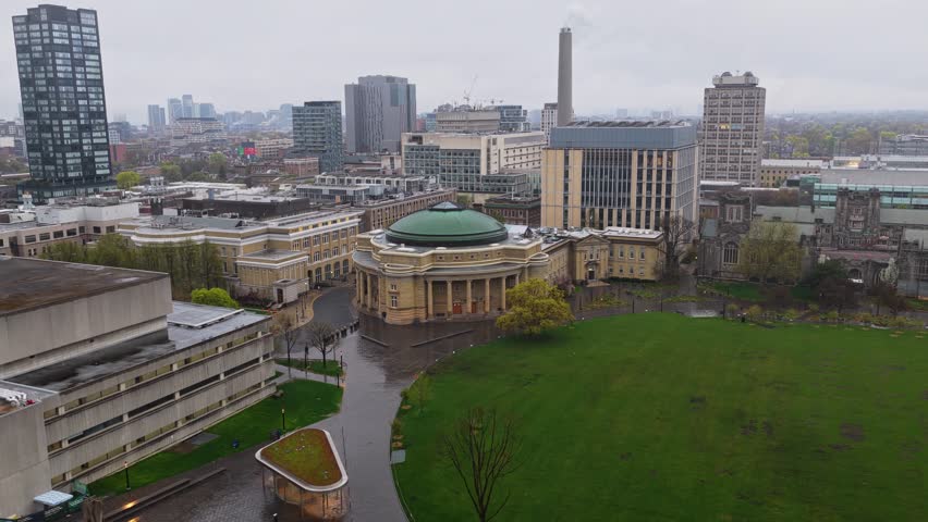 Overcast skies above University of Toronto campus revealing Convocation Hall with green roof, modern skyscrapers and downtown financial district skyline in Canada