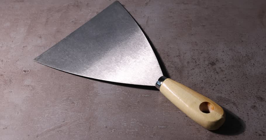 Putty knife on grey table, closeup. Construction tool