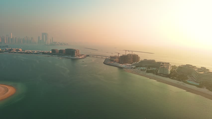 Aerial panorama of luxury villas and private beaches on Palm Jumeirah man-made island in Dubai, UAE, during golden hour.