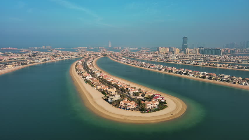 Aerial panorama of luxury villas and private beaches on Palm Jumeirah man-made island in Dubai, UAE, during golden hour.
