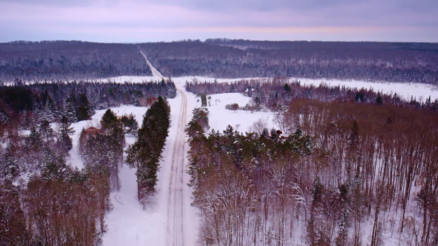 Drone shot flying over country road in northern michigan in winter