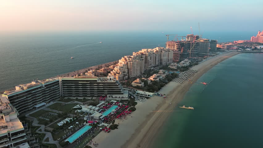 Aerial panorama of luxury villas and private beaches on Palm Jumeirah man-made island in Dubai, UAE, during golden hour.