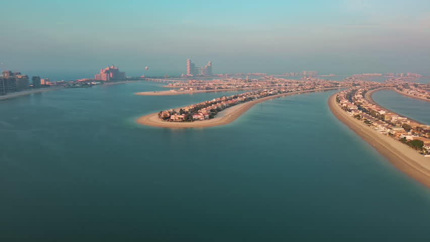 Aerial panorama of luxury villas and private beaches on Palm Jumeirah man-made island in Dubai, UAE, during golden hour.