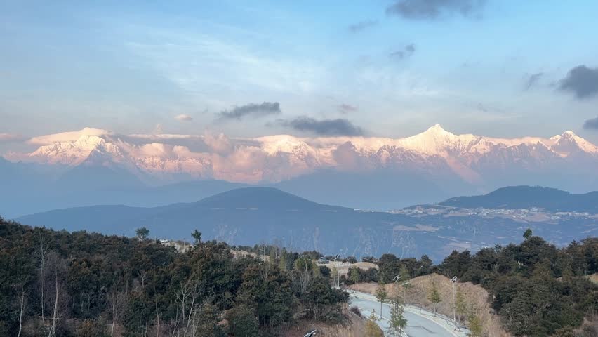 Golden sunlight hitting the snow-capped peaks of Meili Snow Mountain above a Tibetan town in Yunnan.