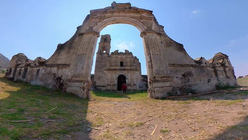 Slow motion shot of a male tourist walking through the arch of a ruined hacienda in puebla, mexico