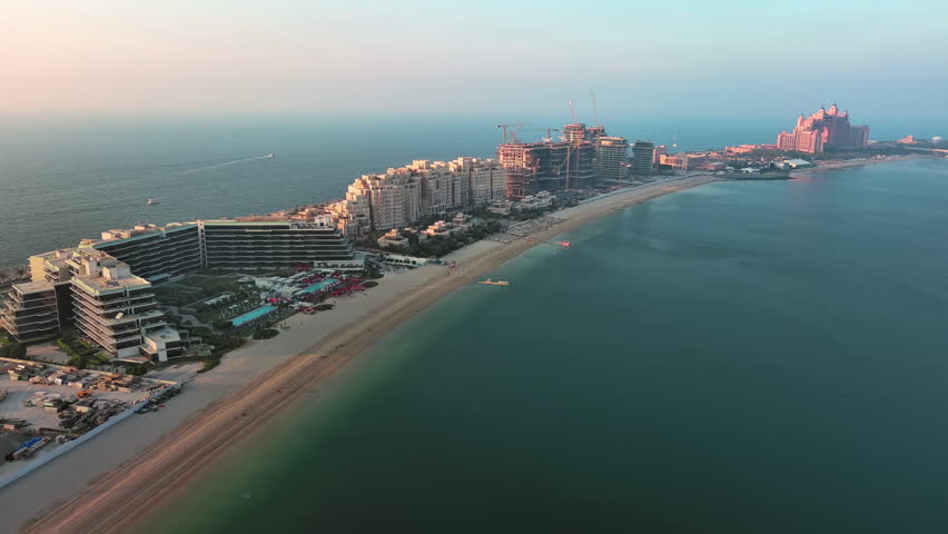 Aerial panorama of luxury villas and private beaches on Palm Jumeirah man-made island in Dubai, UAE, during golden hour.