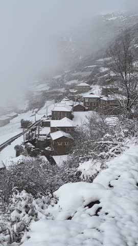 Stunning high angle vertical shot of Jiarong Tibetan stone houses and terraced fields covered in white snow in Sichuan.