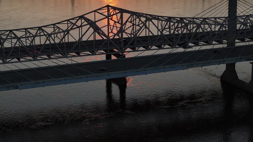Aerial view of the truss bridge crossing the Ohio River at sunset with cars driving across the span in Louisville, Kentucky, United States.