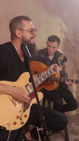Vertical video. Bearded singer and guitarist performing live music