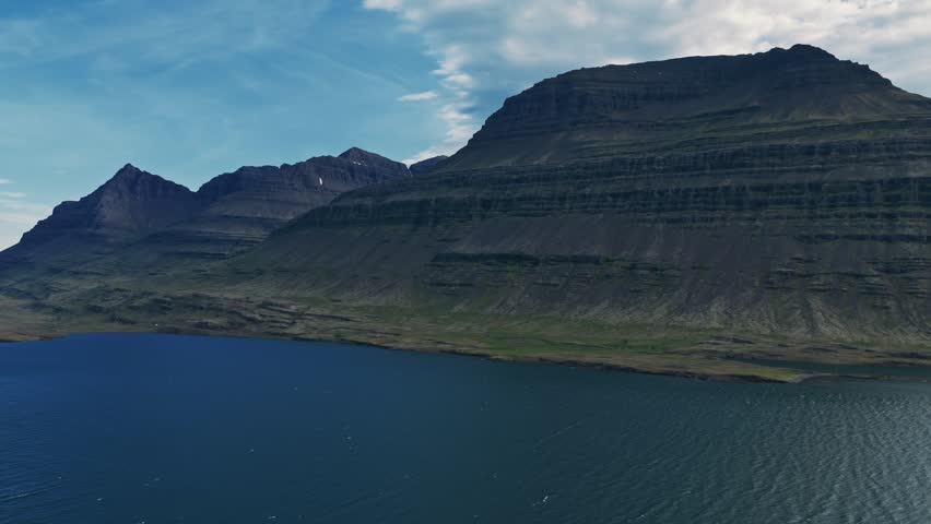 Aerial view of Icelandic mountains and blue fjord along rugged coastline