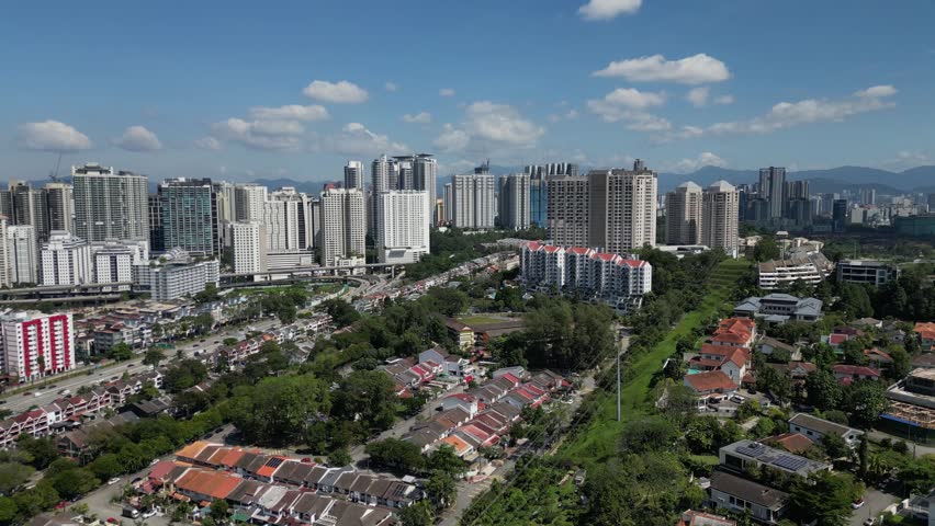 Aerial view of the modern skyline with skyscrapers and residential houses surrounded by lush greenery under a blue sky Kuala Lumpur, Federal Territory of, Malaysia.