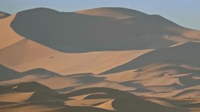 Golden sunbeams cast long, dramatic shadows across the rolling peaks and ridges of vast sand dunes - Powered by Shutterstock - Get 15% off with code: PIKWIZARD15
