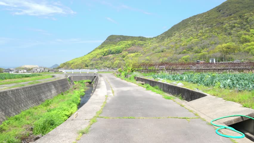 Walking along rural farm road in Japanese countryside with mountains