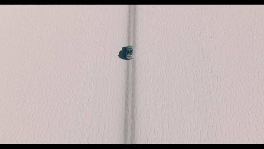 4x4 vehicle driving across the Uyuni salt desert in Bolivia, crossing vast white plains under a clear sky. Minimalist landscape with endless horizon and remote travel adventure.