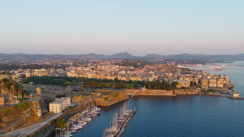 Aerial establishing of Corfu harbor with marina boats and coastal city under clear daylight