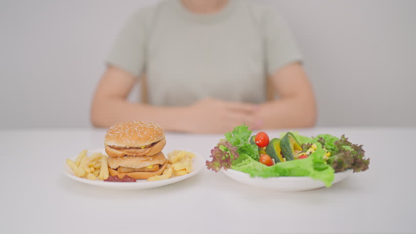 happy woman with Healthy and Unhealthy Food Choice. Comparison of Calories and Nutrition of vegetables Salad plate and Hamburger. diet planning, weight loss management, junk food and habit lifestyle